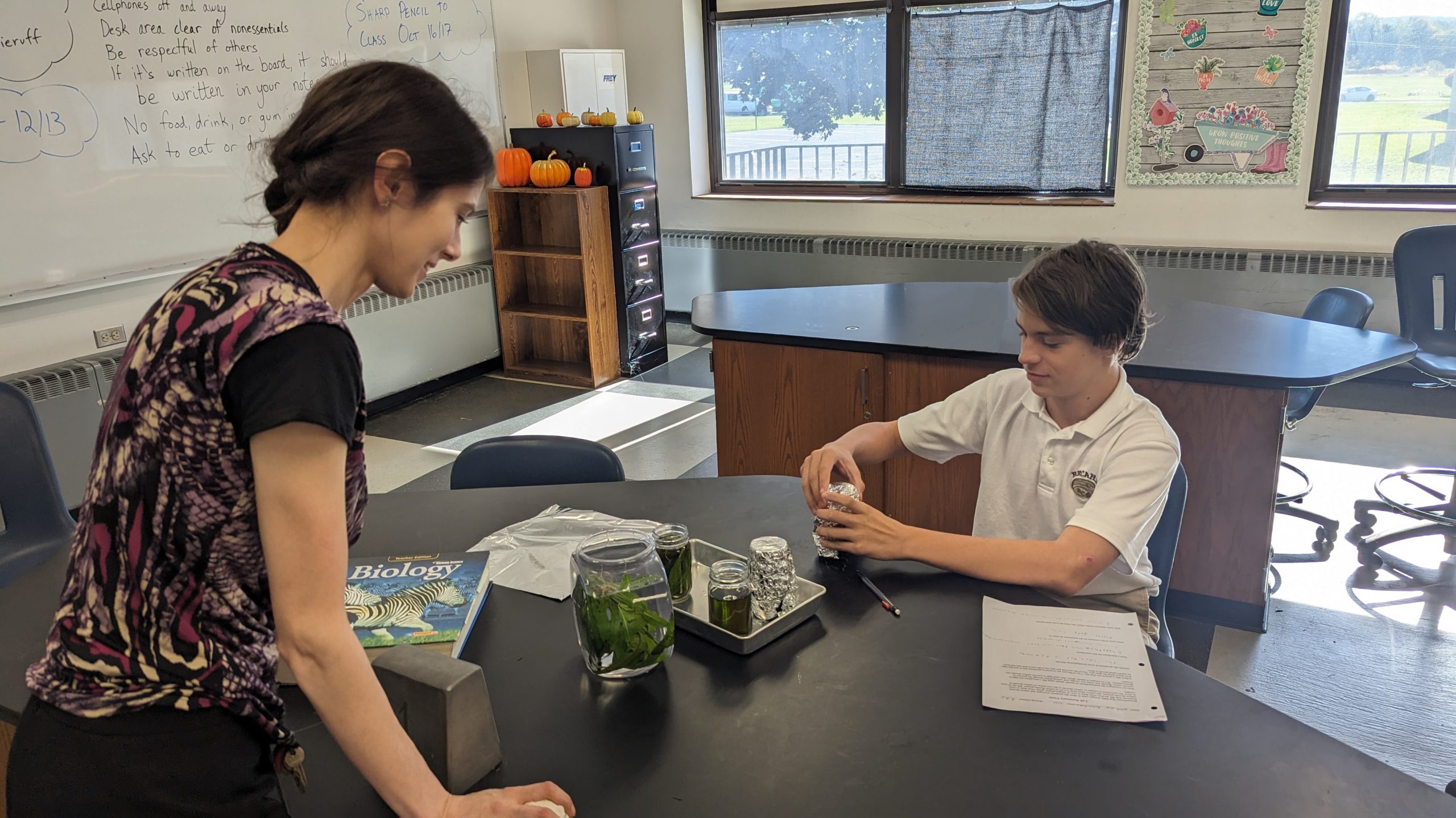 Becahi Biology teacher, Ms. Kurtz overseeing a student doing an experiment.