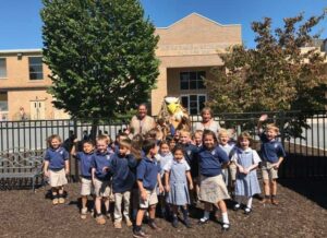 Image of Bethlehem Catholic High School's Golden Hawk with student from Notre Dame Elementary school. The school is in the background.